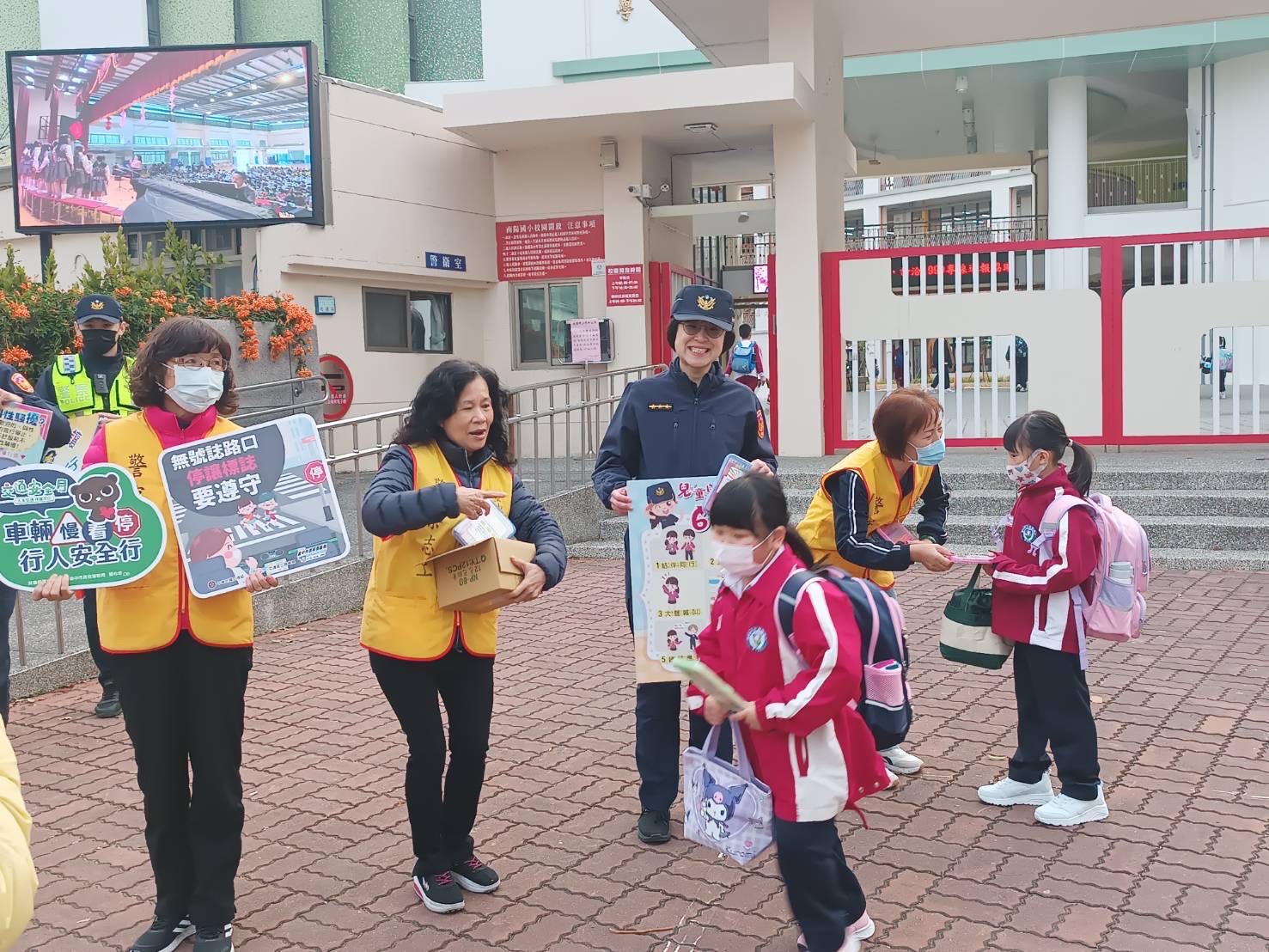 在南陽國小校門口協助交通疏導及維護安全並發放宣導品（彩色鉛筆組）給學童，並向他們宣導行人交通及婦幼安全觀念。（圖/記者謝福祐翻攝）